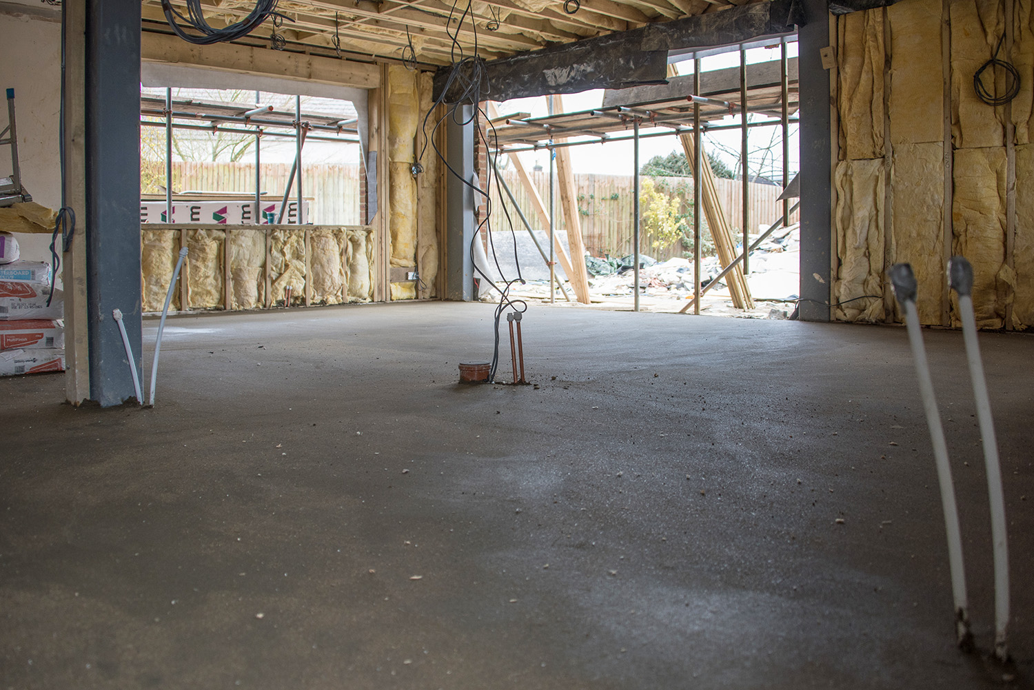 Interior of the Pembury extension during construction, showing new open-plan floor slab, exposed steel beam, and insulation fitted to walls